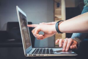 Hands pointing at a laptop screen while reviewing digital content during a collaborative work session