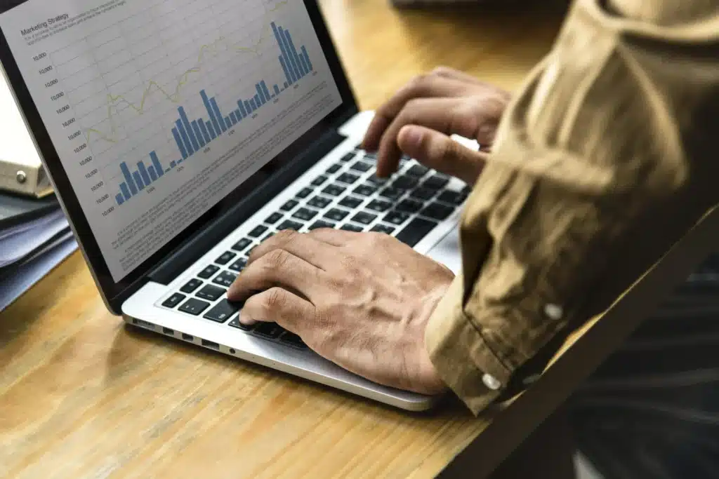 Marketer analyzing performance data and growth metrics on a laptop to track and optimize marketing campaigns